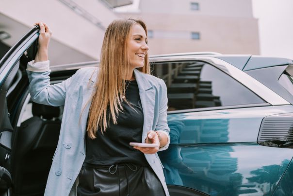 A person walking out of their leased car, with their hand on the door.